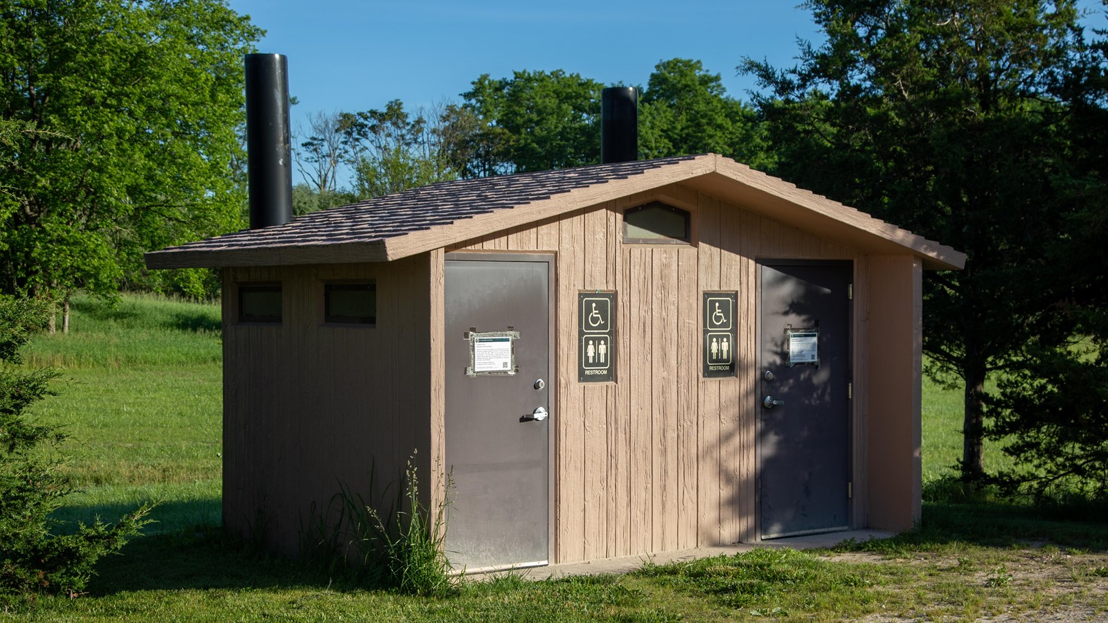 A small rectangular building with two doors into restrooms.