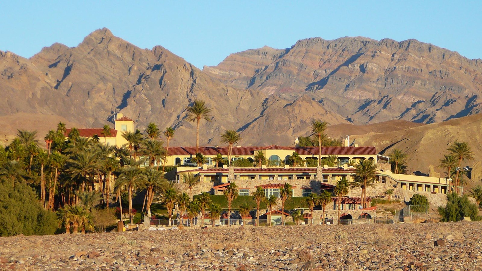 a large castle like structure with palm trees in a desert setting