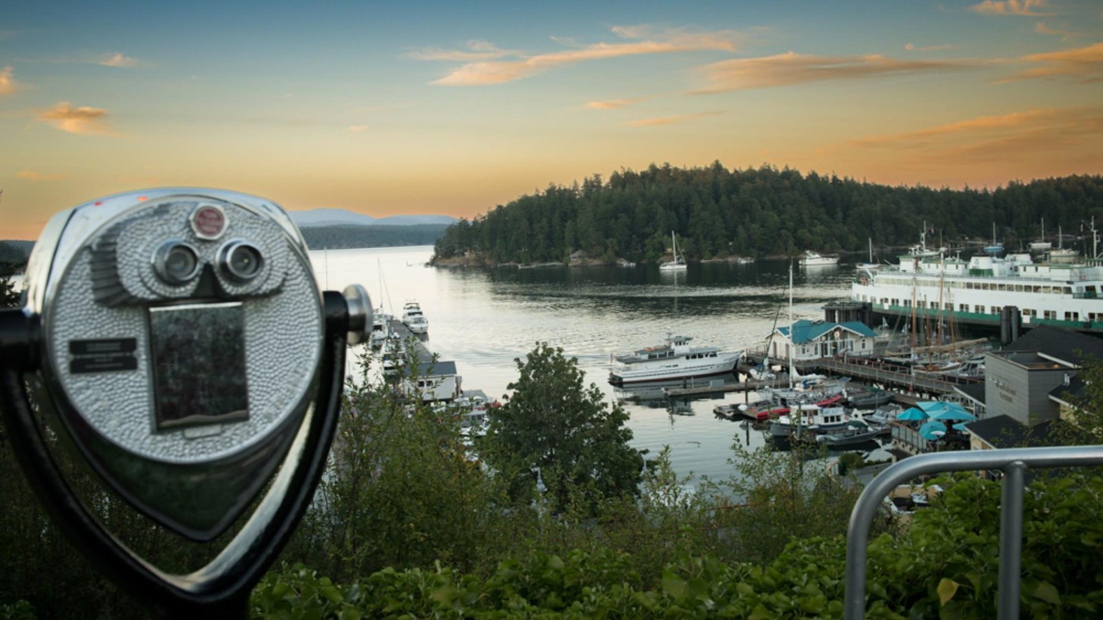 Color photo of a viewing scope overlooking a busy harbor at sunset