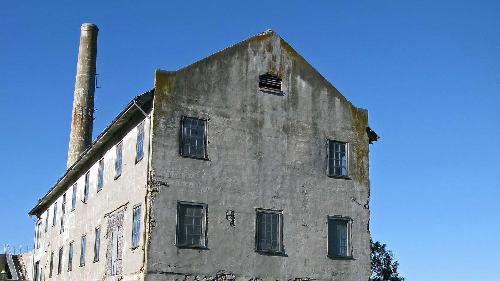 The crumbling white concrete Quartermaster Building stands stark against the blue sky.