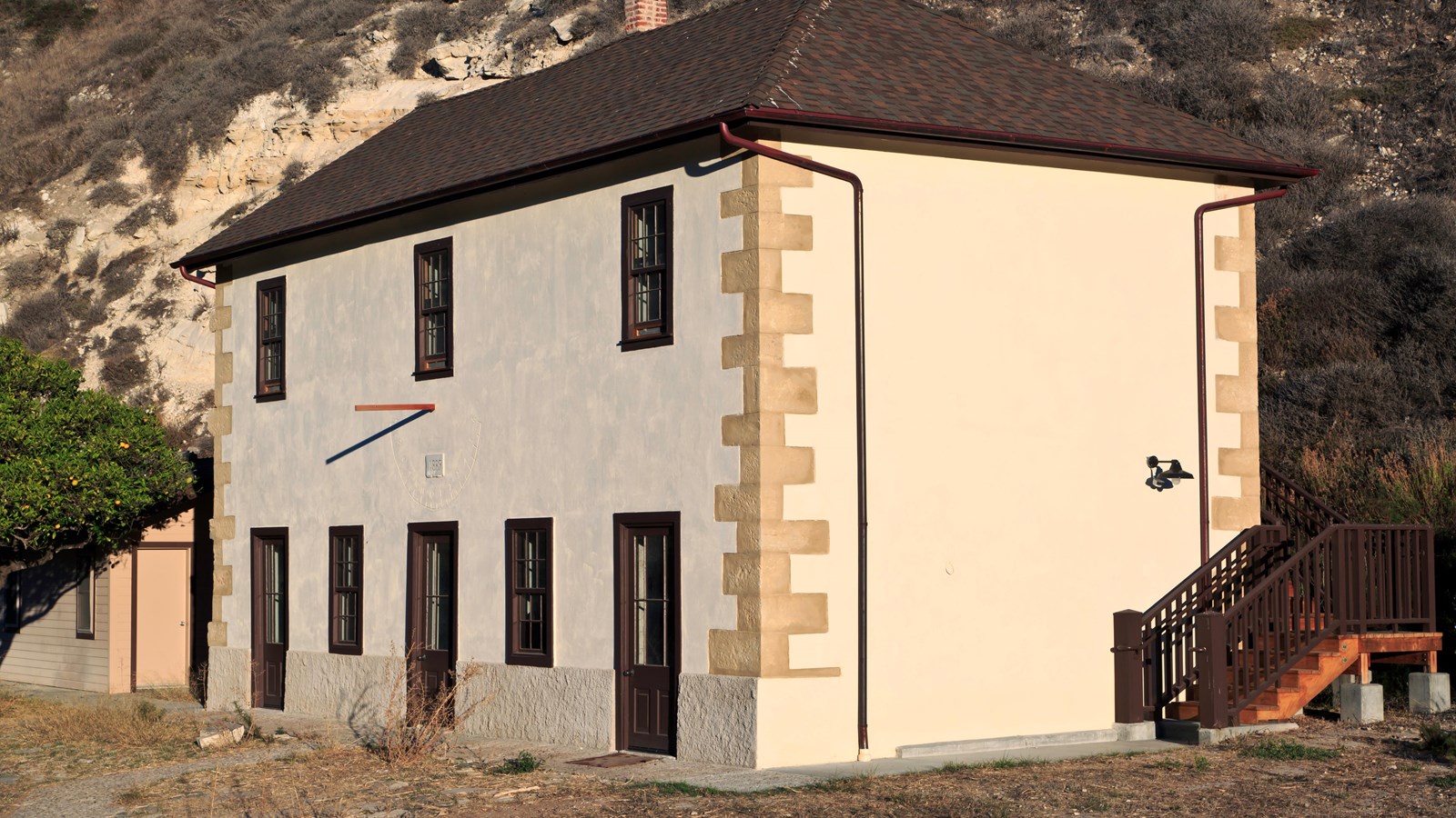 This creamy white two story residence is tucked into a ravine with rugged hills on three sides.