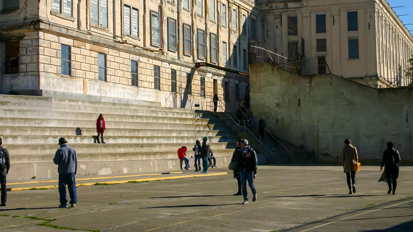 Visitors walking across the concrete recreation yard with steep wide stairs. 