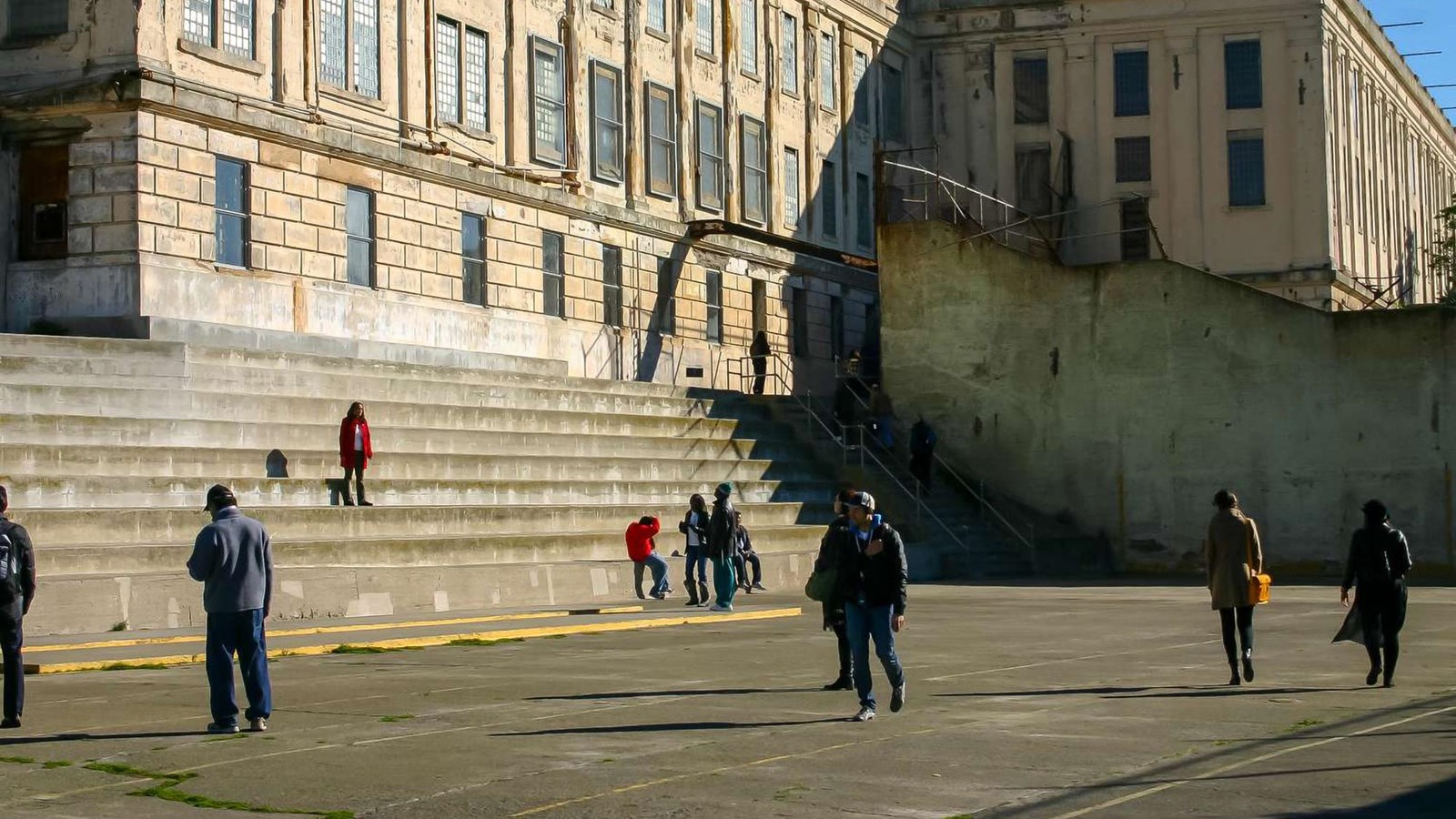 Visitors walking across the concrete recreation yard with steep wide stairs.