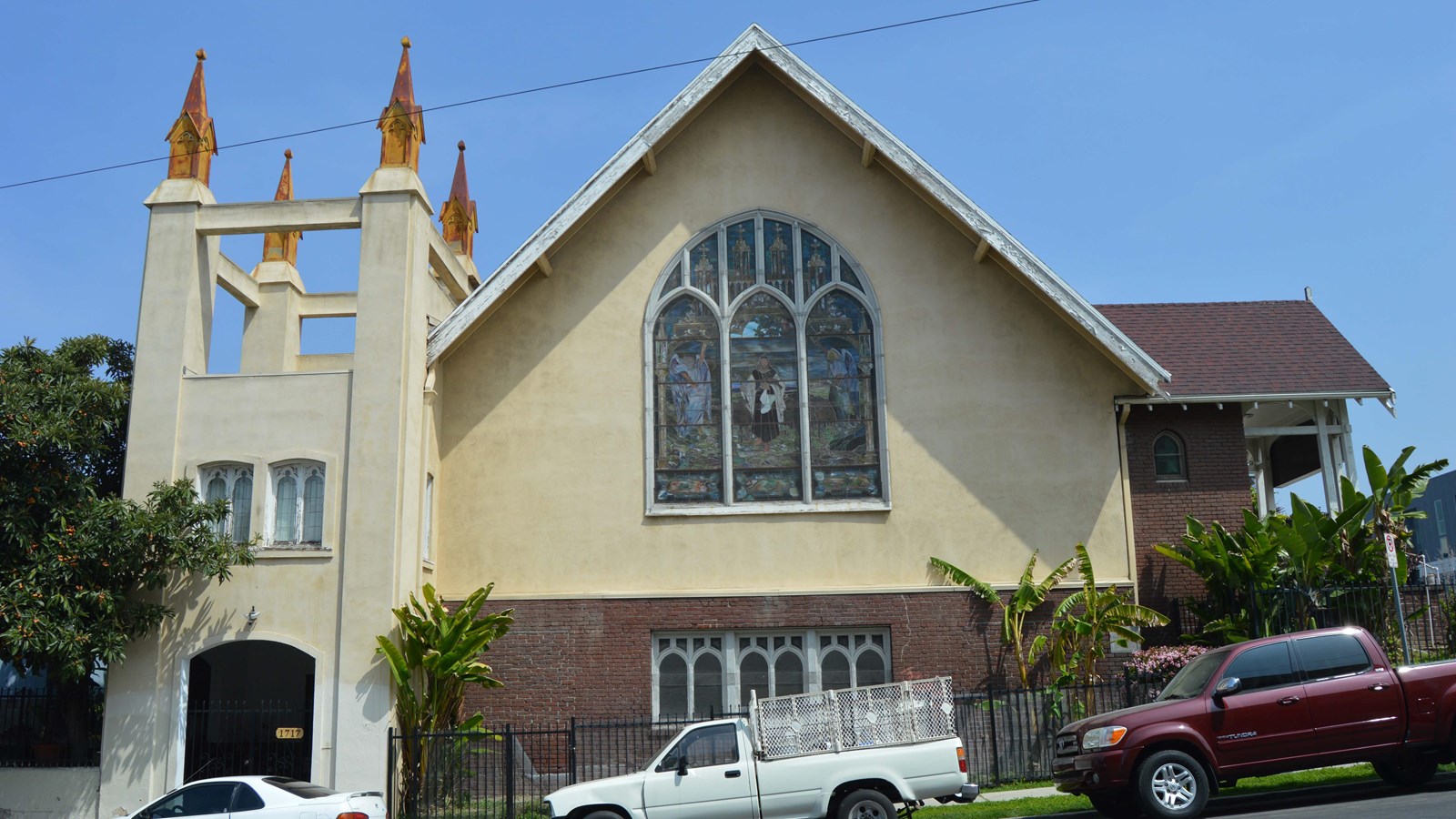 Exterior wall of church with a centered large stained glass window and a square bell tower