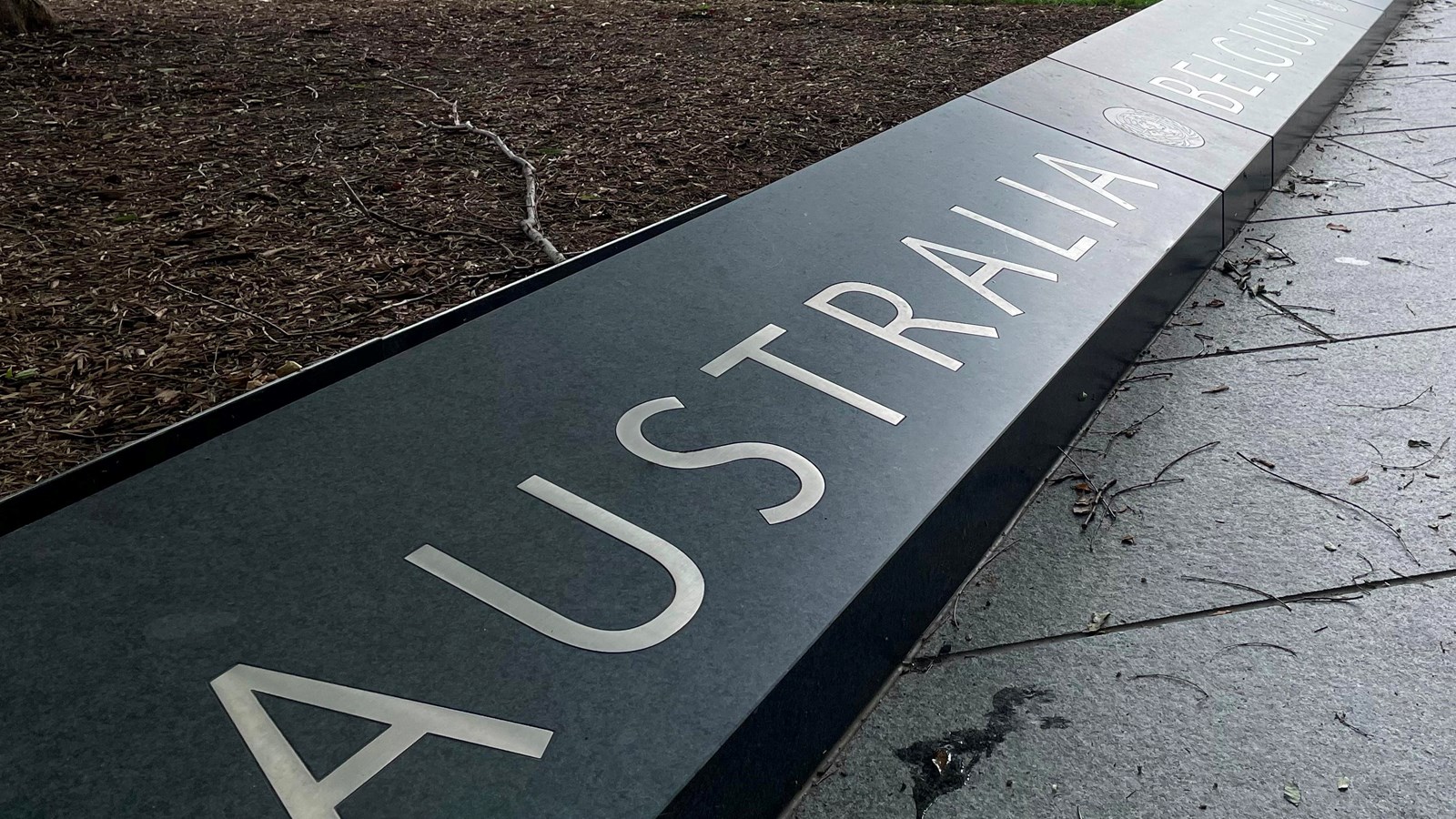 A low stone curb with names of 22 countries etched on it, separated by the United Nations logo.