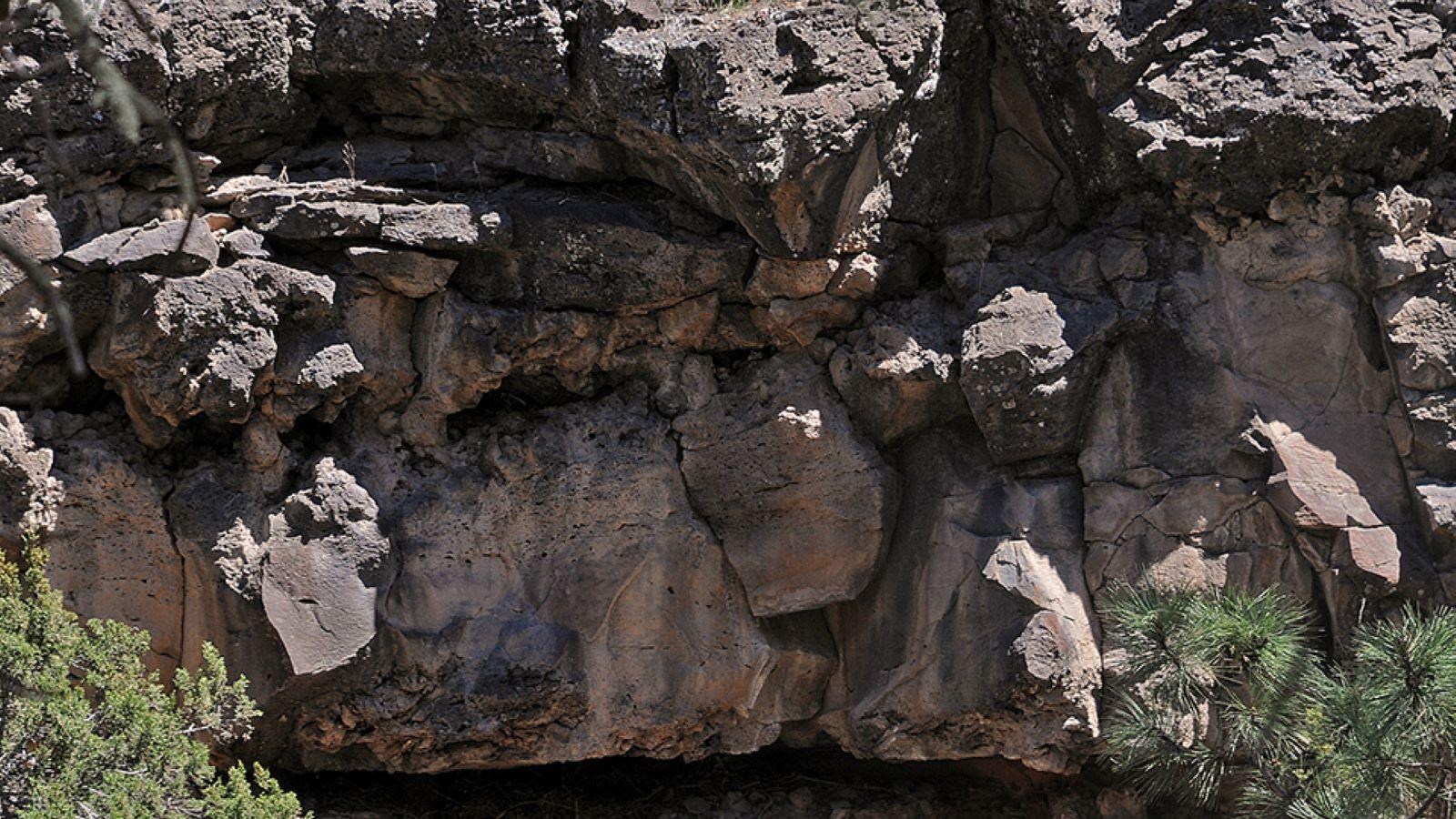 A cliffside of jagged black rocks with lighter brown streaks.