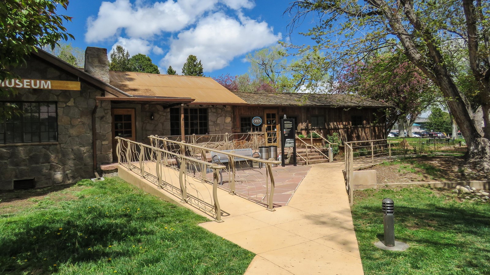 A stone and log house sits at the end of an entry walkway.