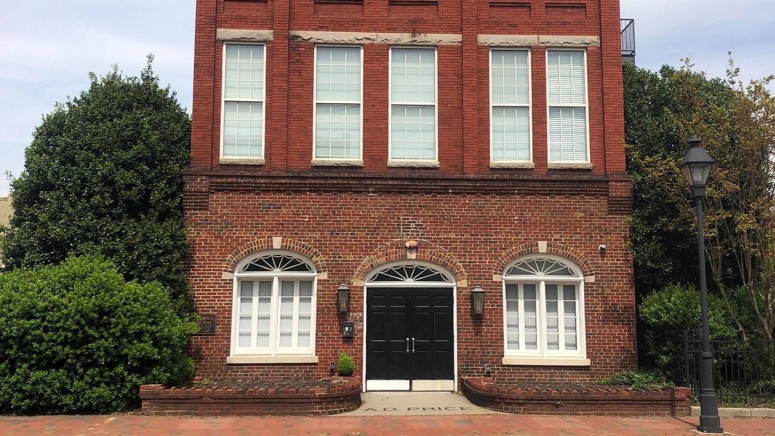 3-story red Brick building, trees on both sides, white window frames 