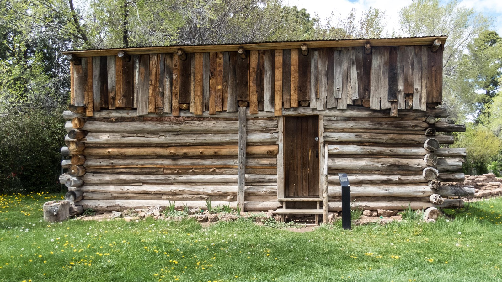 A small log structure sits on a grassy lawn.