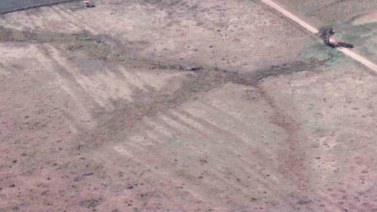 Aerial view of field with a row of deep furrows running through the middle.