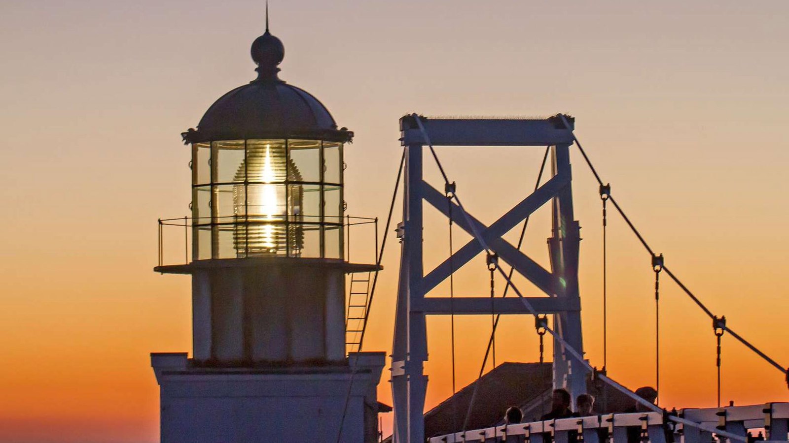 Point Bonita Lighthouse with yellow sunset colors glowing behind it.