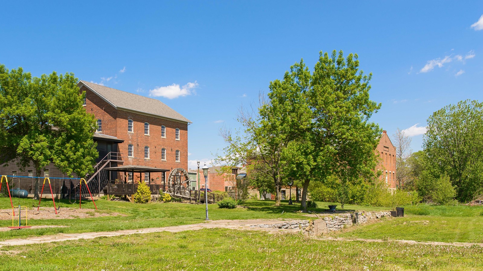Green grassy lawn stretches back to large, historic brick buildings.