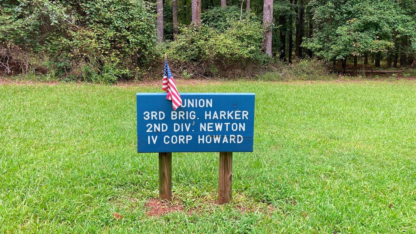 A small blue sign showing Union troop position stands in a grassy clearing