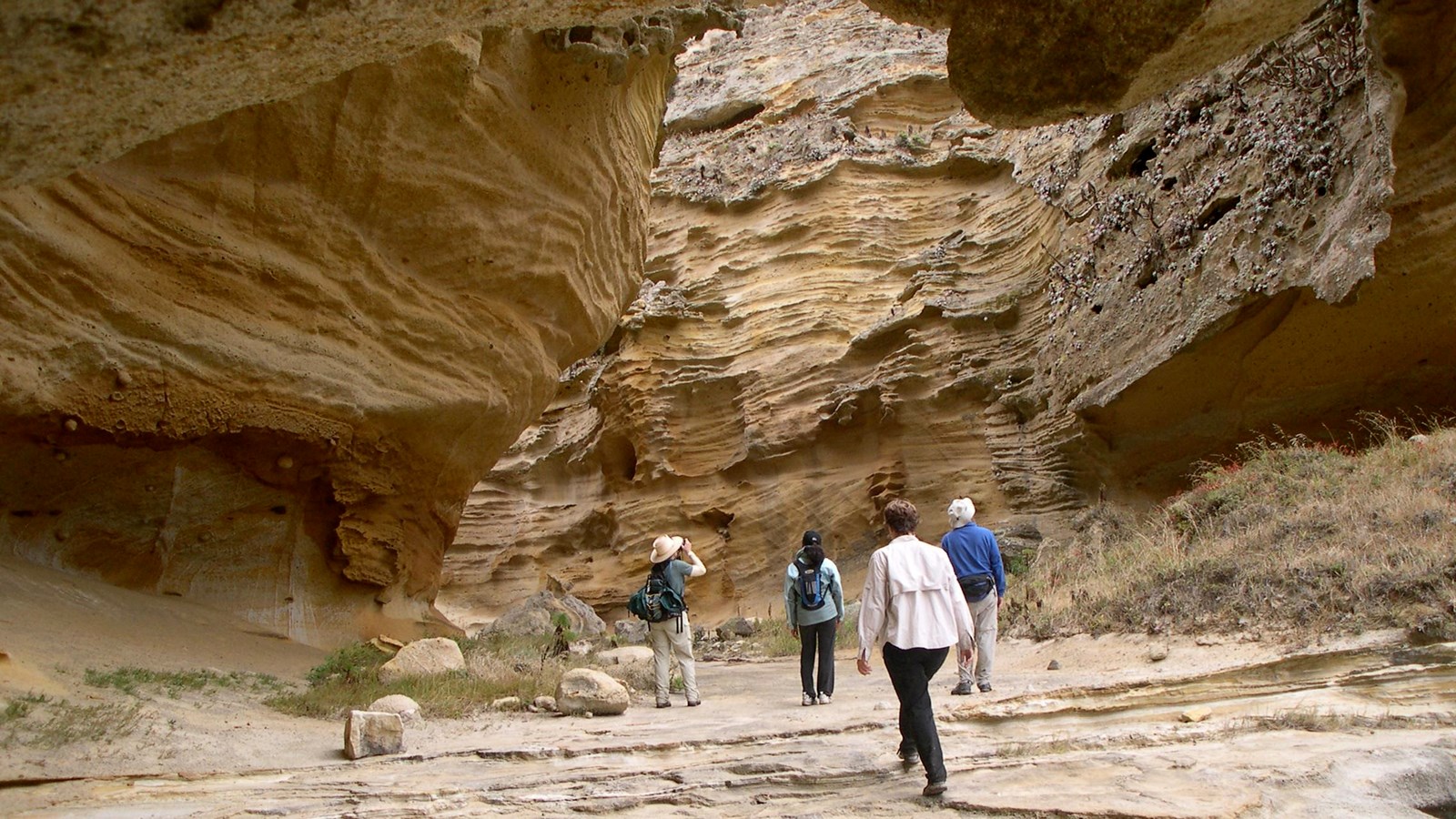 Visitor walking in narrow canyon with steep walls.