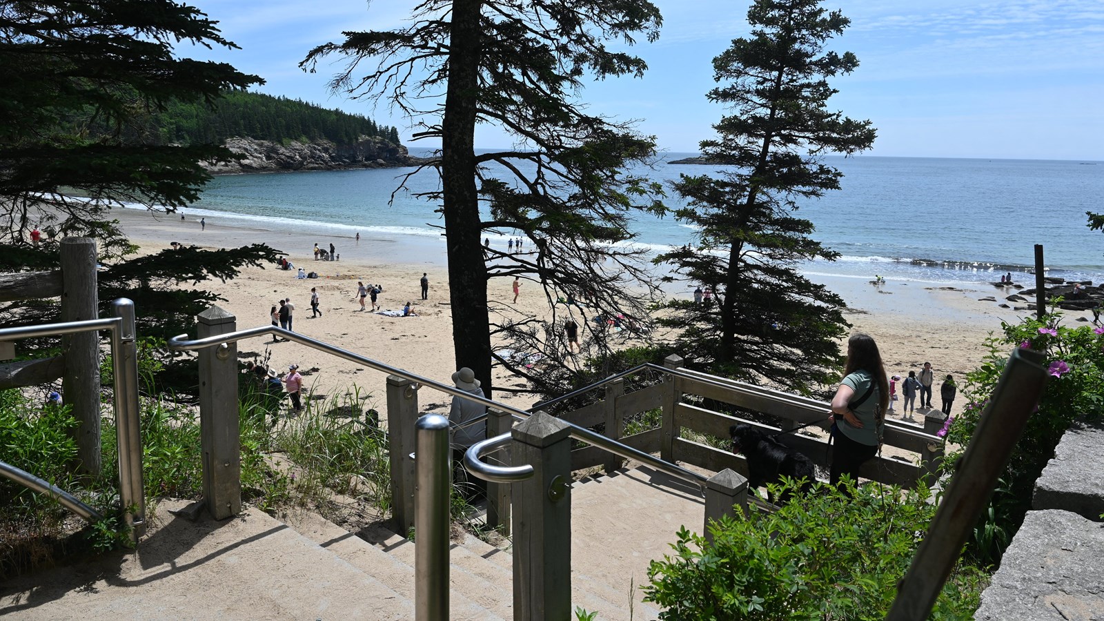 A staircase with a woman standing on it looking out at the view of a beach.