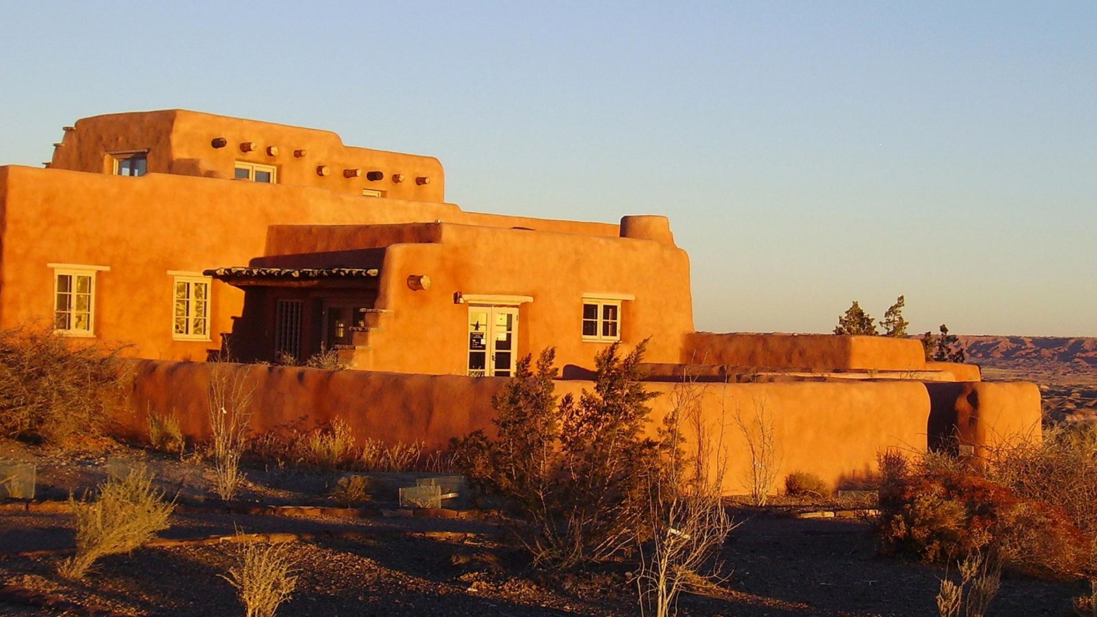 Sunrise lit historic Pueblo-Revival Style building against a twilight sky.