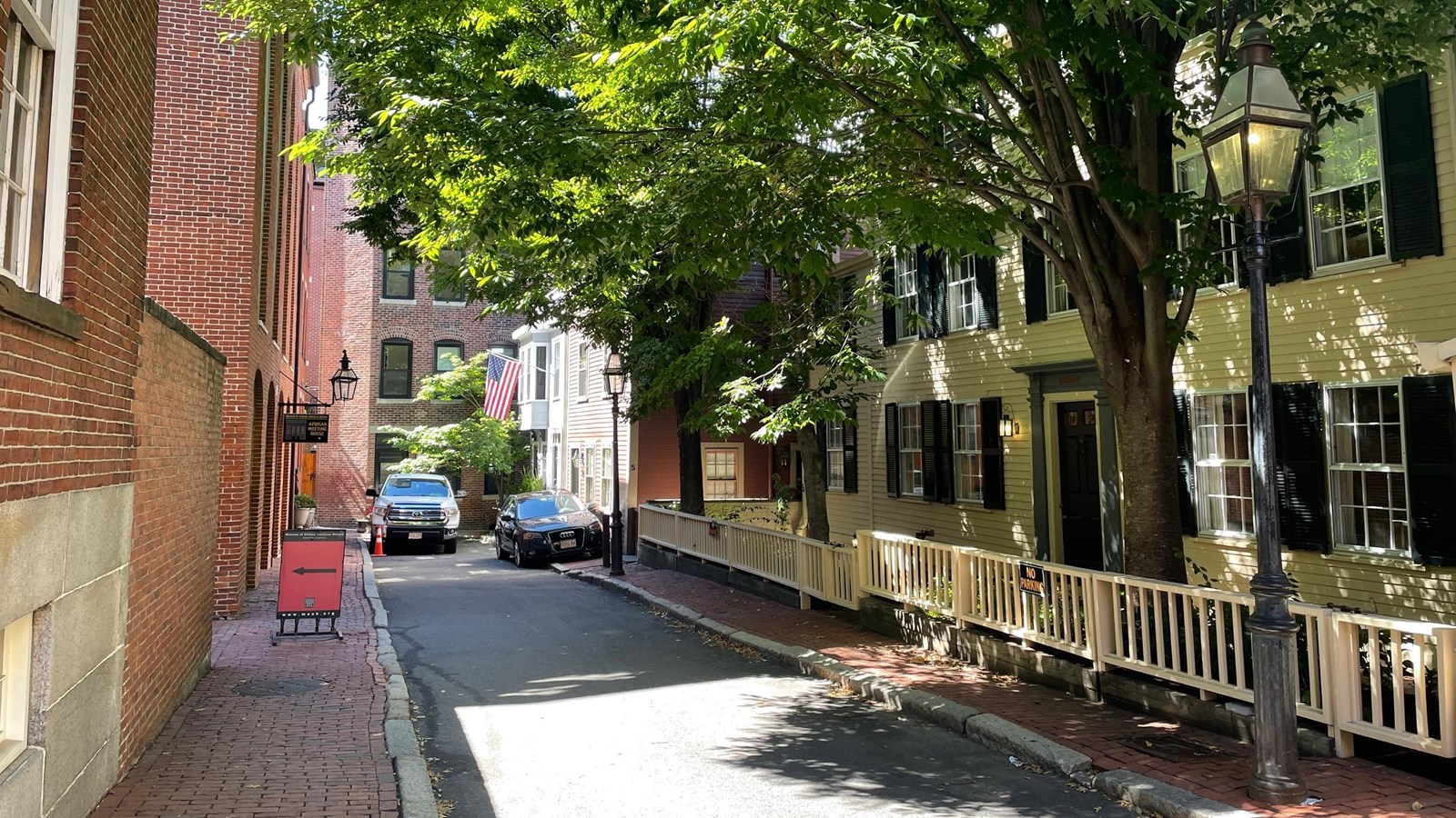 A deadend street with two large brick buildings left and a long yellow sided building right.