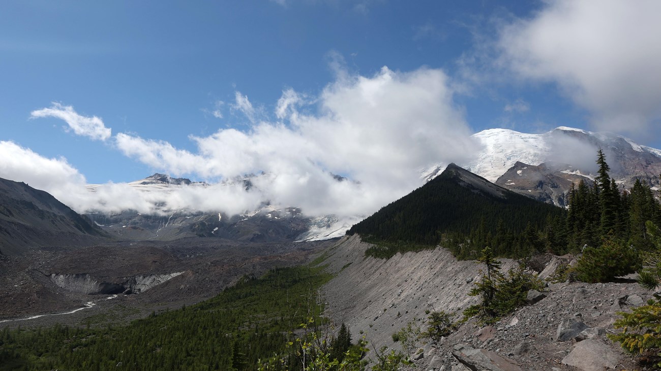 View of mountain with rocky glacier moraine with clouds partially covering glacier