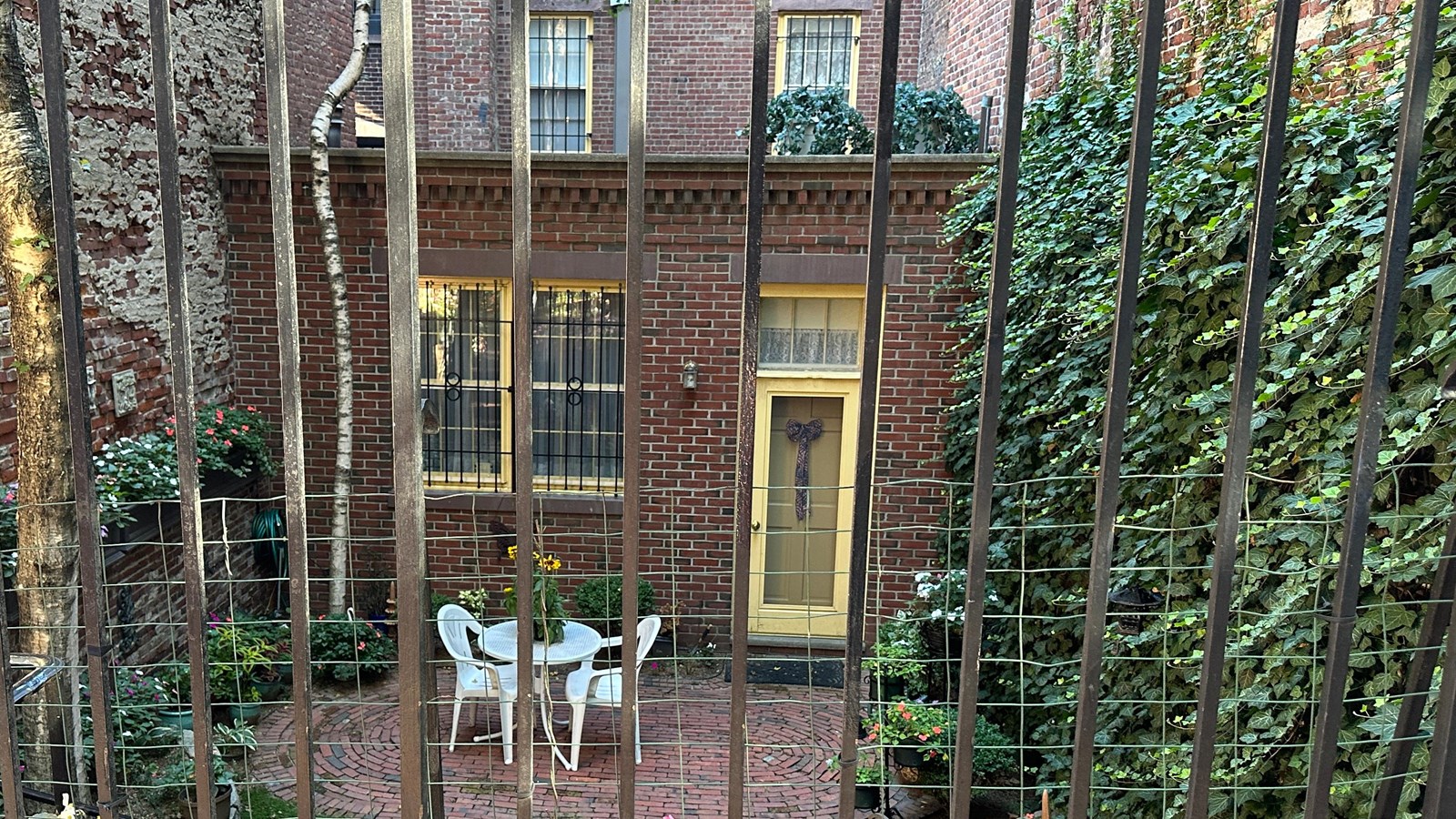 View looking into a few of a small square brick front of a house with a yellow door.