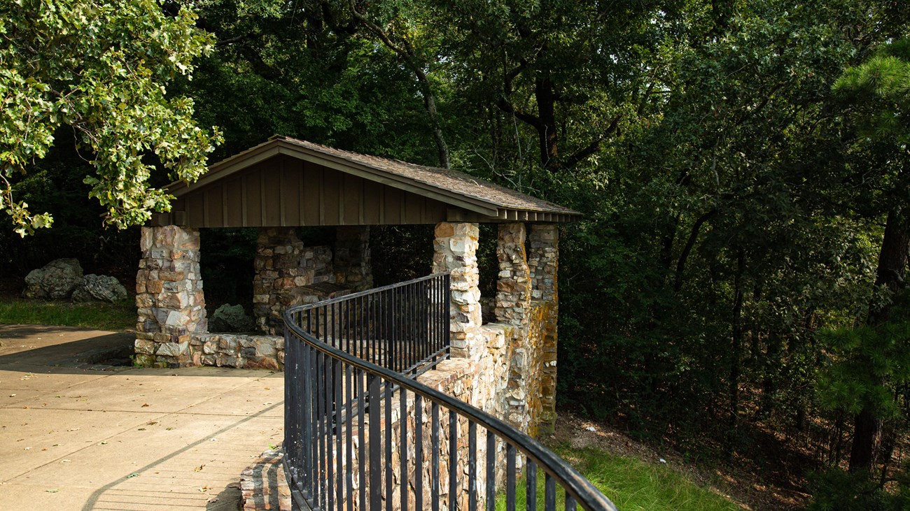A stone shelter sits on a hillside overlooking a rolling landscape.