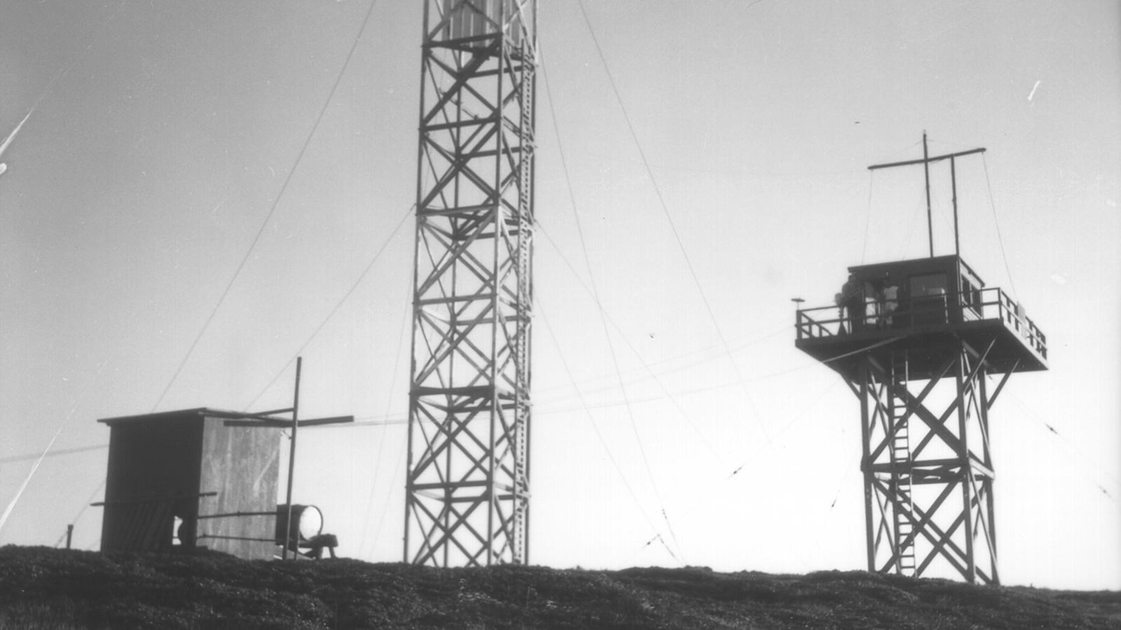 Tow tall towers with scaffolding and one small building.
