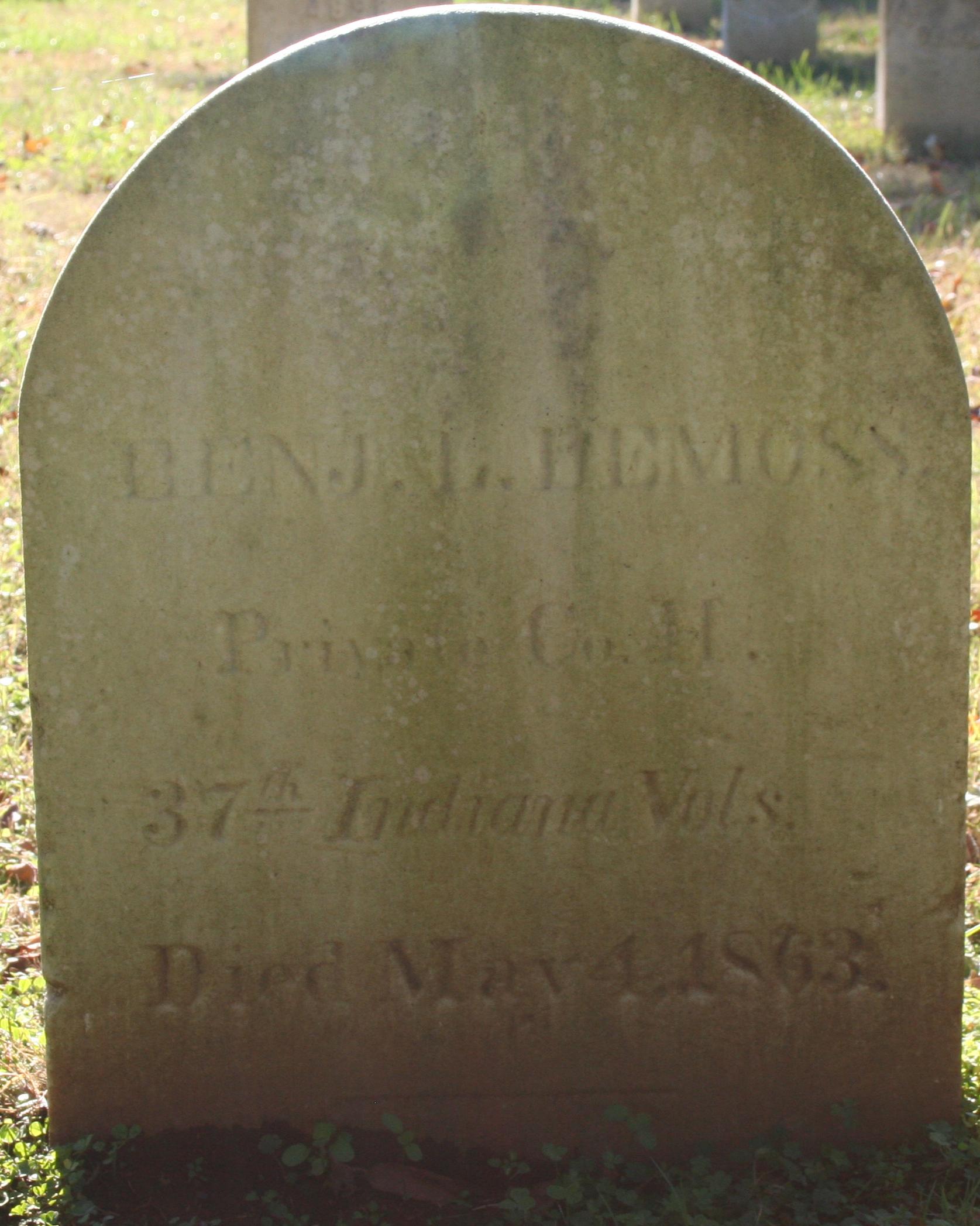 Rounded marble headstone with writing on it. 