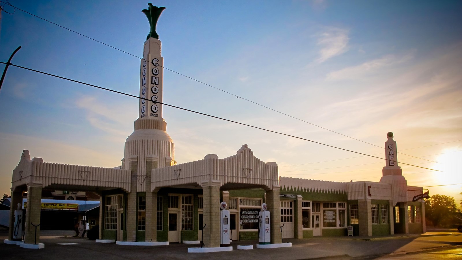 A large white art deco building with a spire that says 