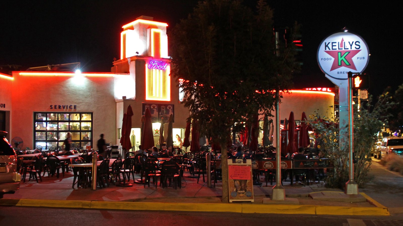 A white stucco building trimmed with red neon lights at night. A white round sign reads 