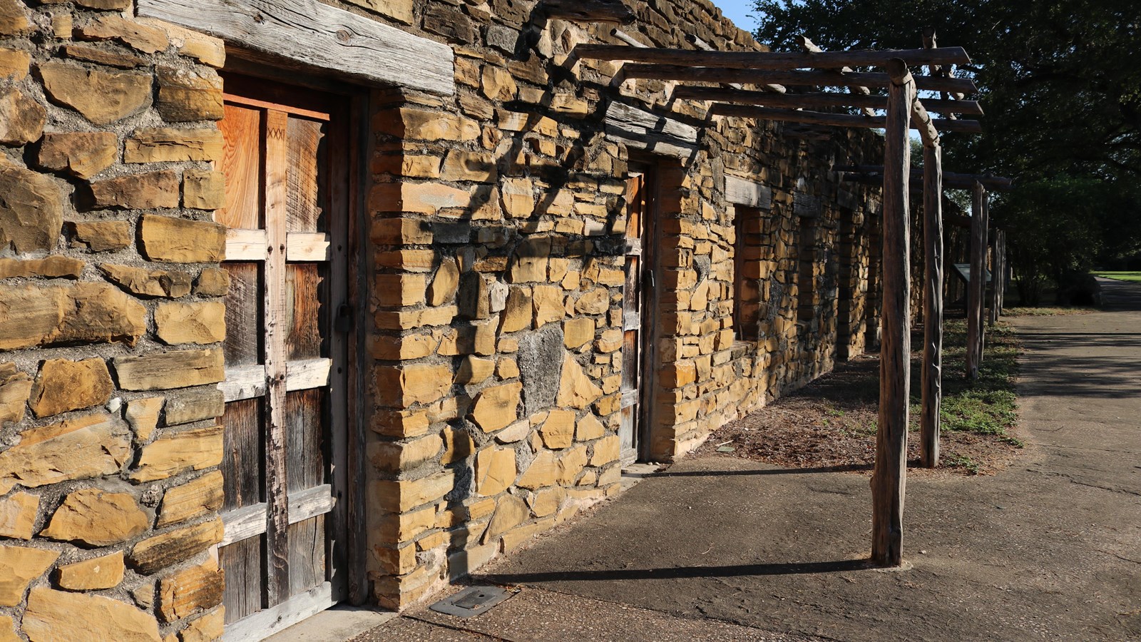 View of long, narrow Indian Quarters building made of limestone with wooden door.