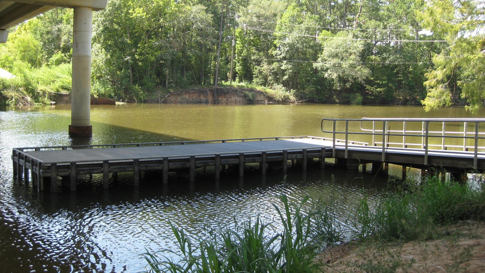 a metal pier floats on the river underneath a highway overpass