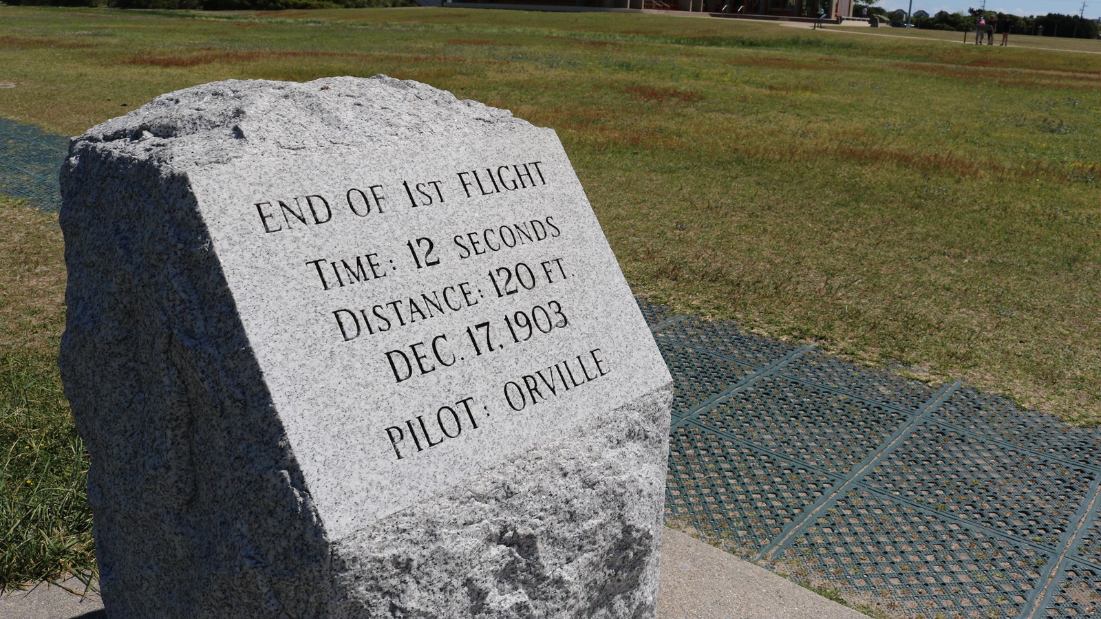 A block of granite with text that marks the pilot, distance and time of the first flight. 
