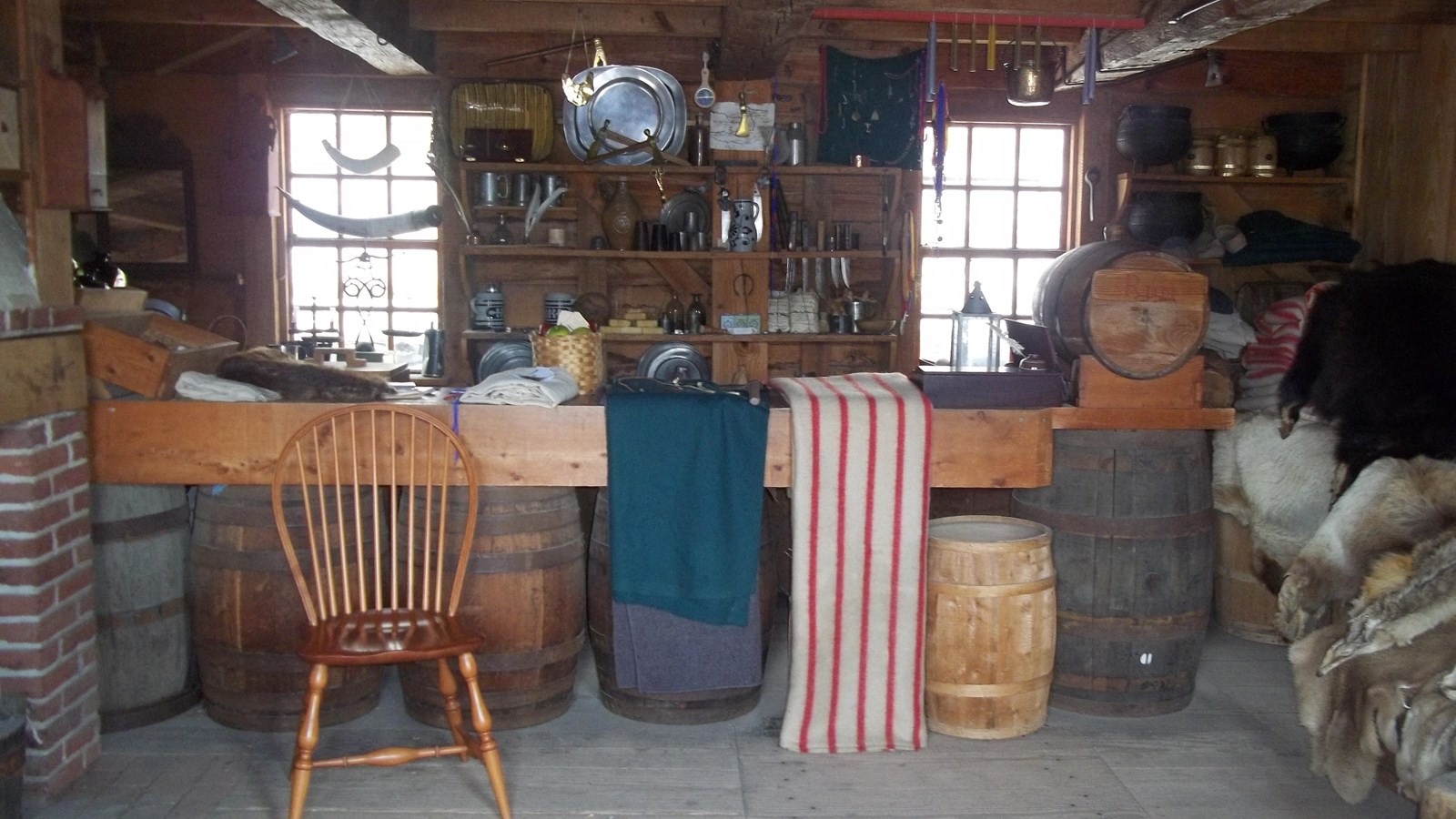 A room filled with many trinkets. A table is set out with mugs on it with two benches for sitting.
