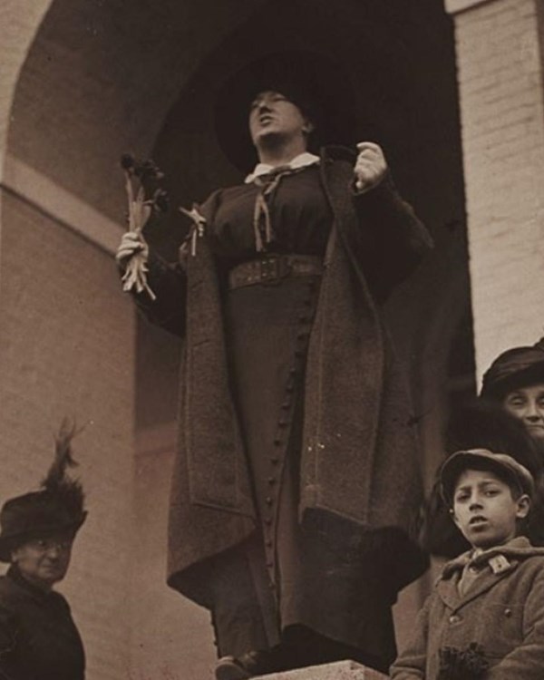 Margaret Foley in a long cloak standing on a ledge speaking.