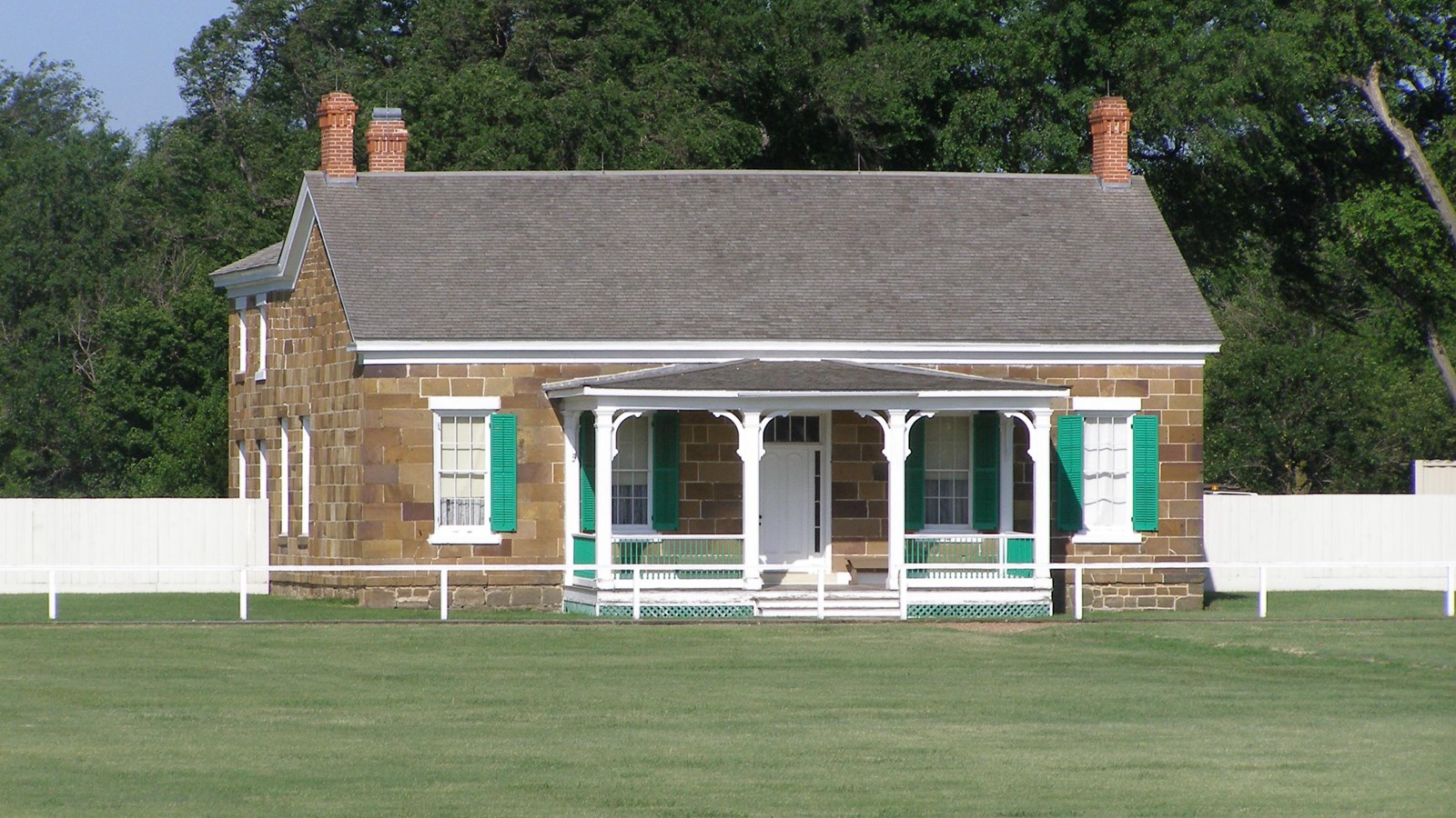 Two-story sandstone building with covered porch.