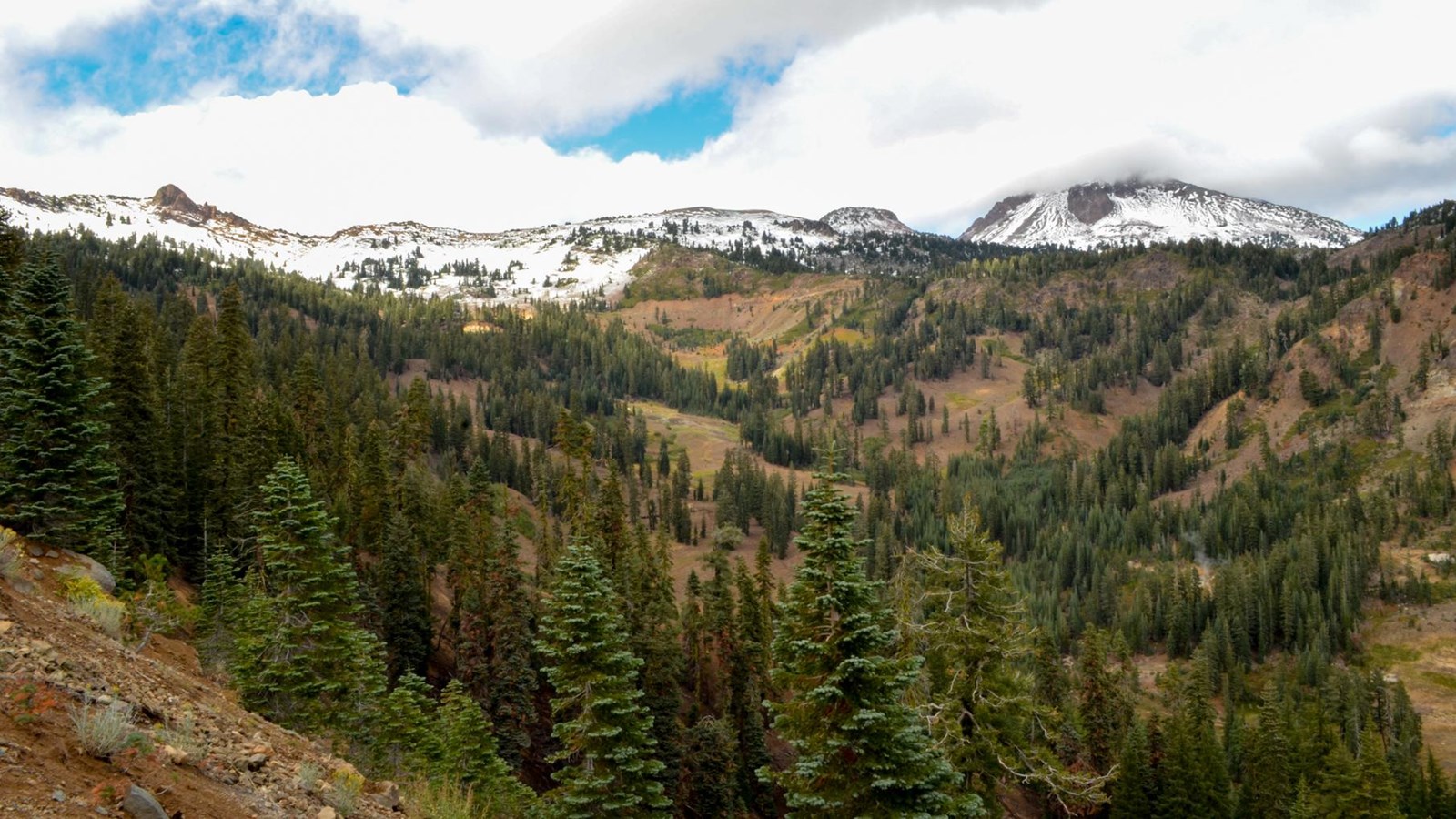 A dusting of snow covers volcanic peaks above a steep, narrow valley. 