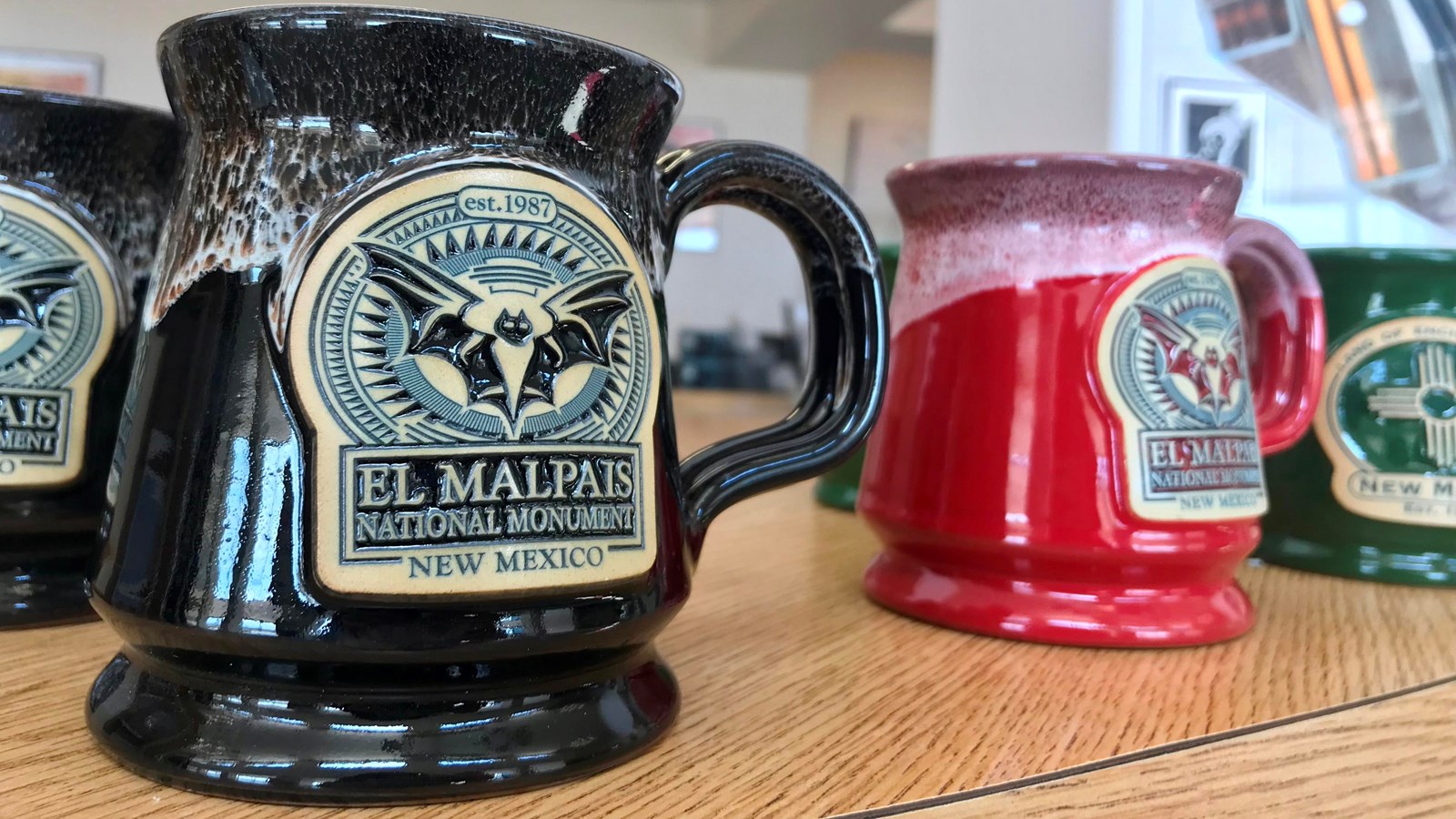 close up of coffee mugs with bat logo on display at a store.