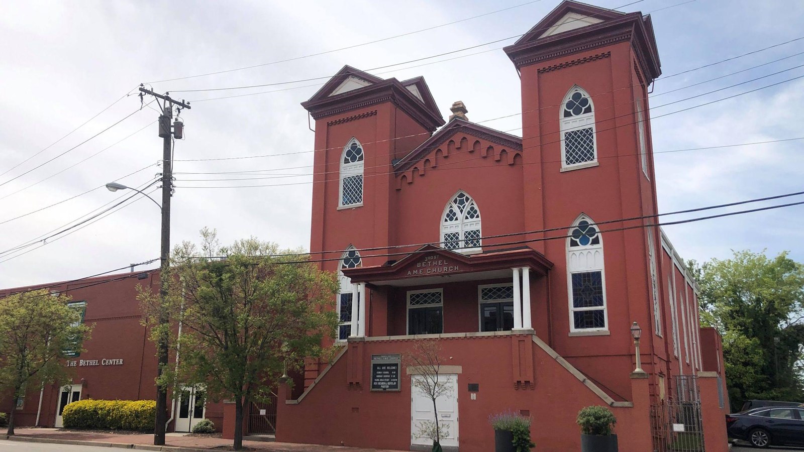 Red brick church, two four story towers with a central 3 story building.