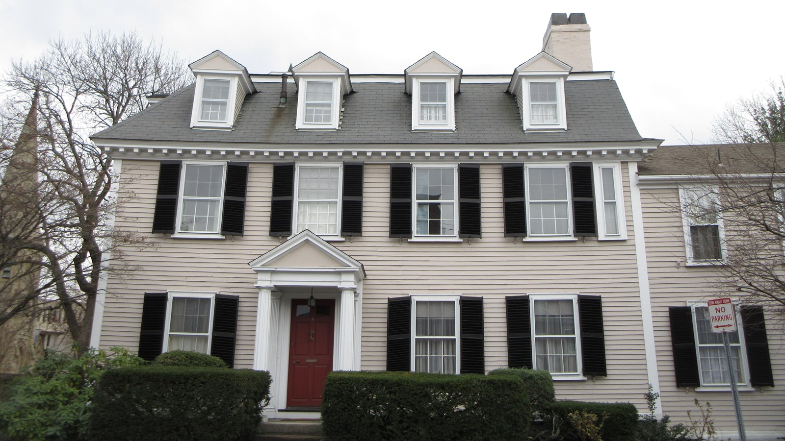 wide grey house with two stores and a row of dormer windows