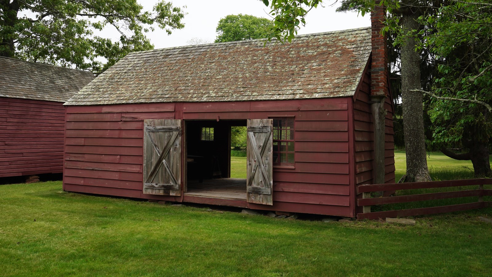 A mid-sized red barn with its doors open.