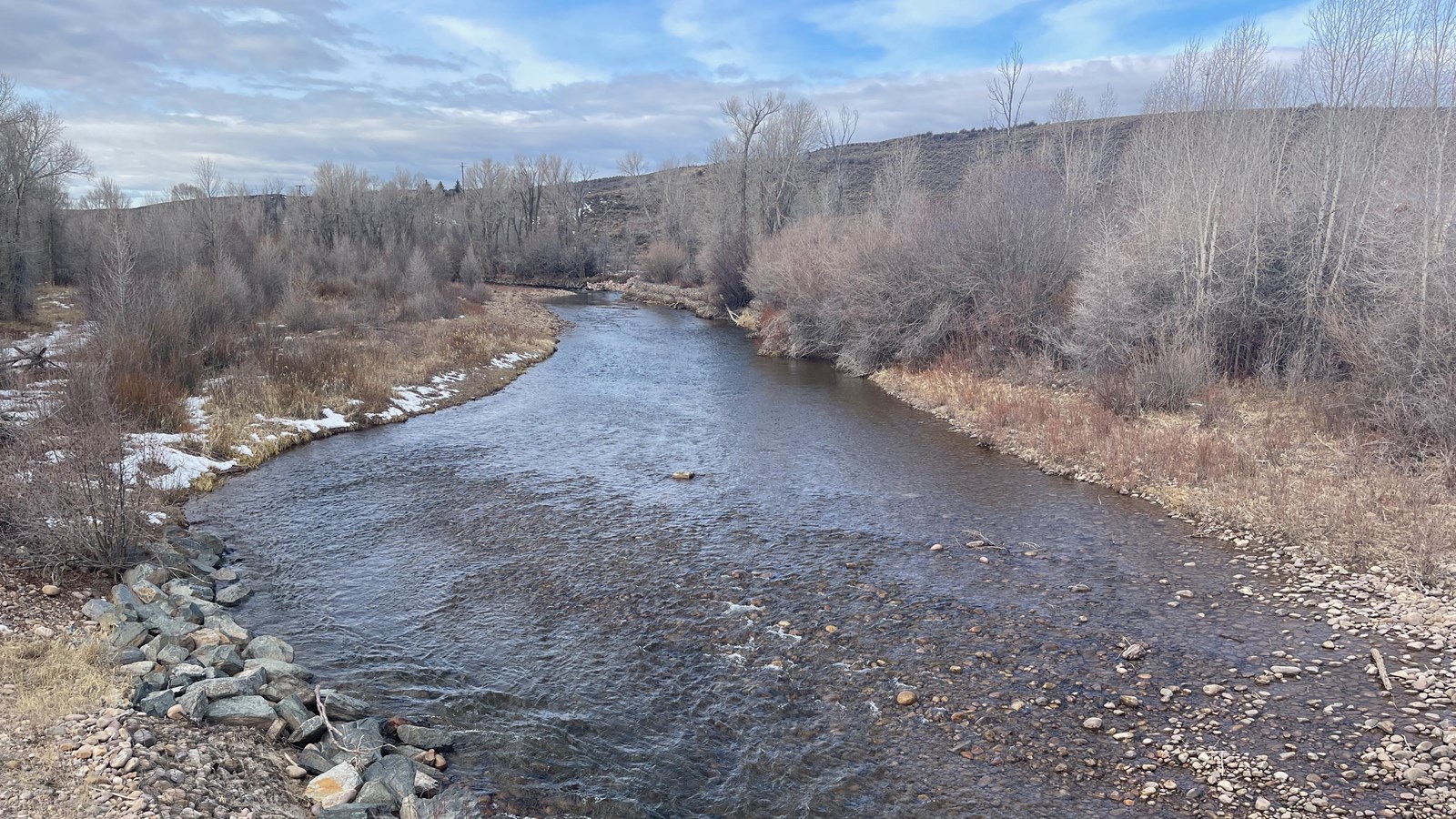 Bear River, clear stream, winter bare trees, rocky banks, ridge, overcast sky.