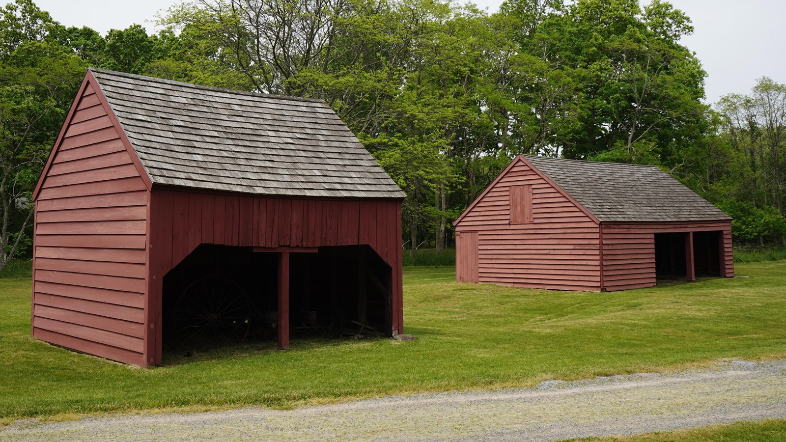 Two open barns stand in a field of grass