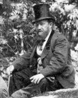 A black and white photo of a man wearing a black suite and top hat. 