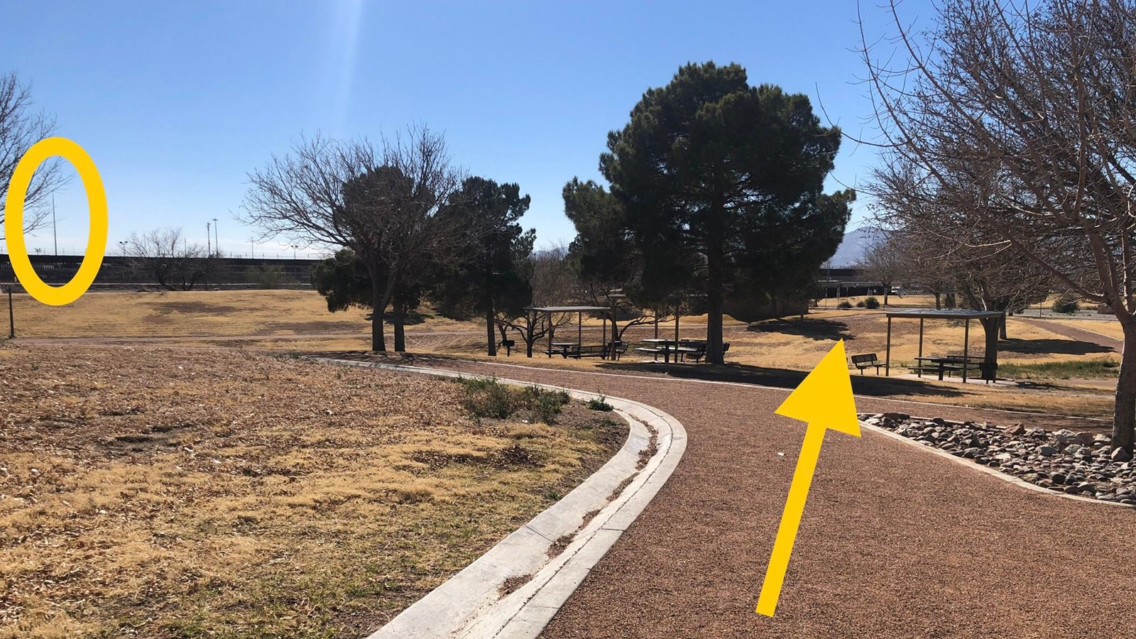 Landscape from red gravel trail. Oval shows flagpole on left side. Arrow points to right to mountain