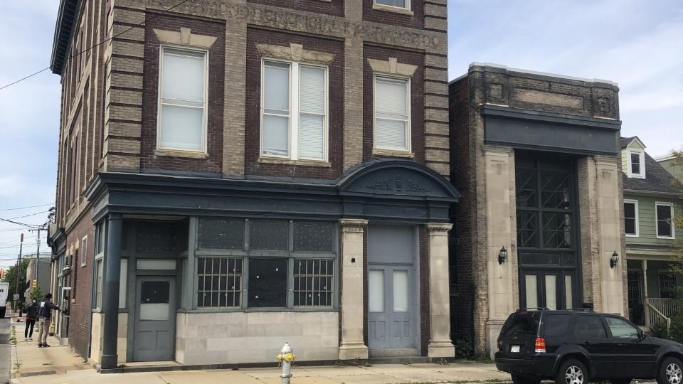 Two buildings, both grey brick, left building 3 stories, right building 2 stories