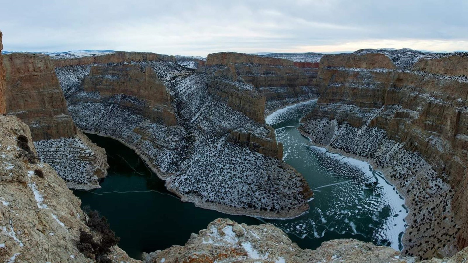 Snow covered red canyon walls with a iced over Bighorn River 1,000 feet below.