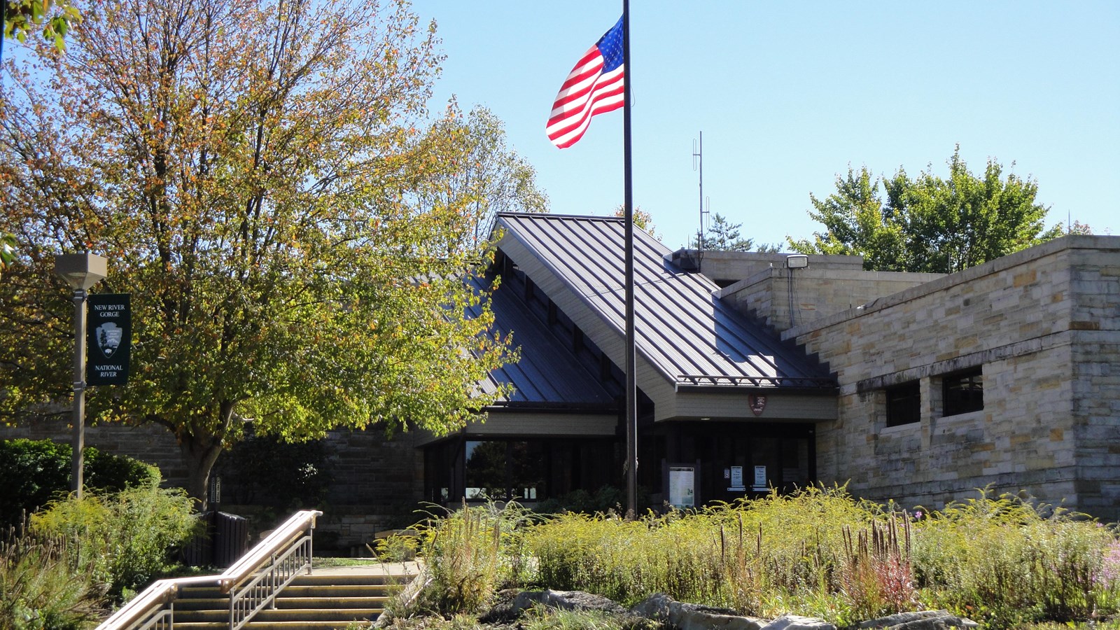 Colored photograph of the entrance to the visitor center with an American flag flying in front.