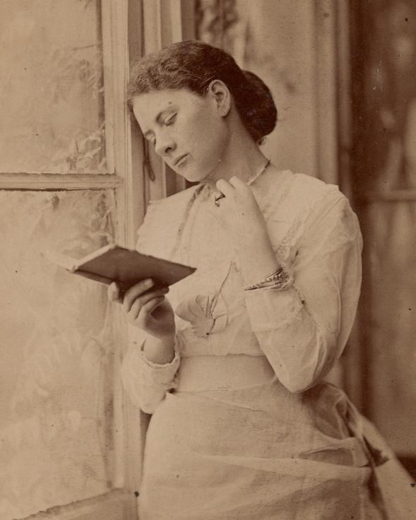sepia photo of woman leaning against wall, reading