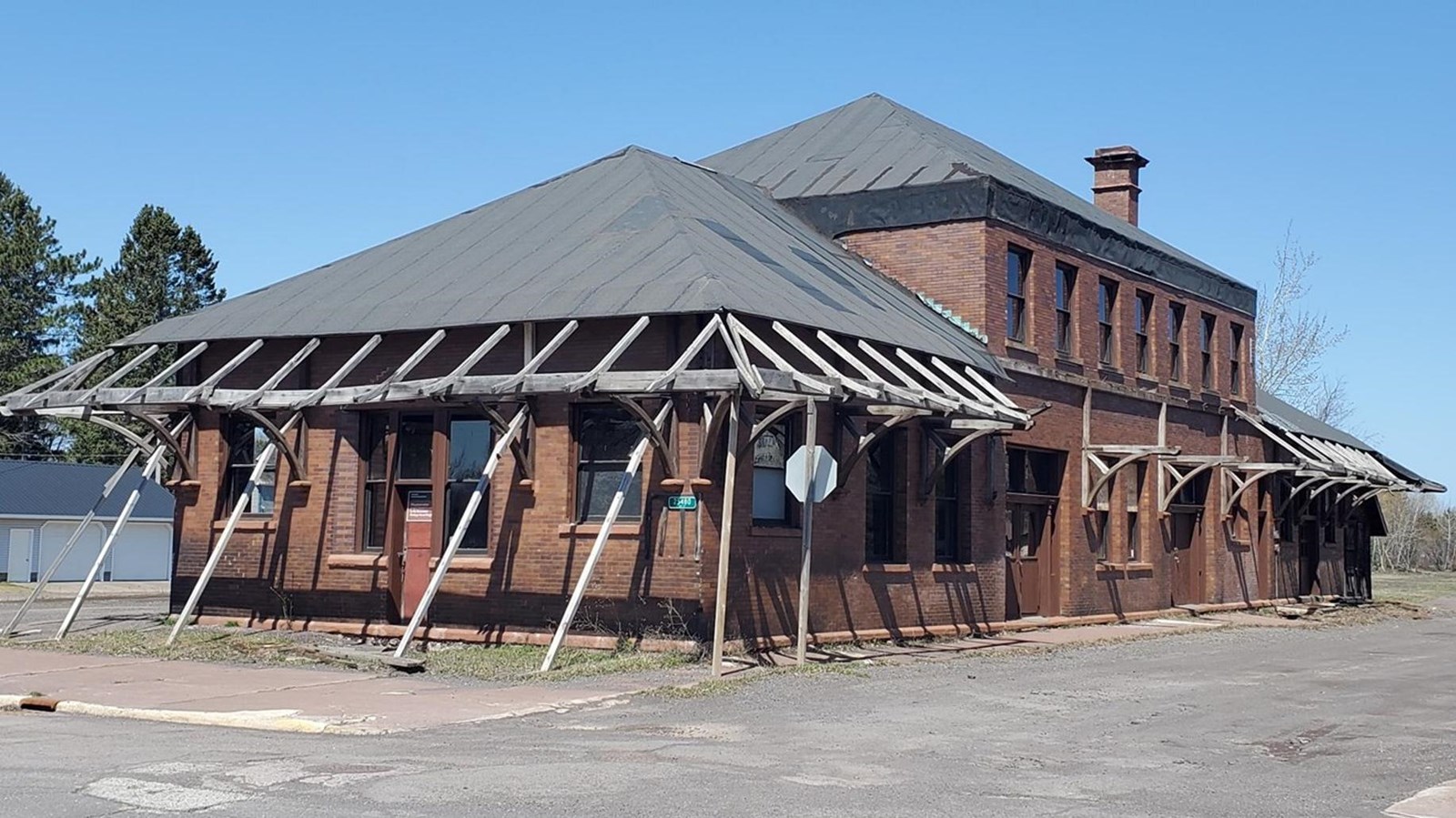 Two story brick building with hipped metal roof.