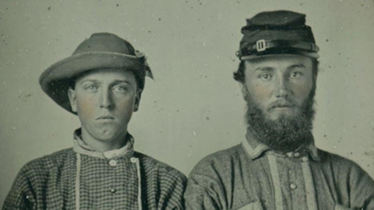 A historic photo shows two young men dressed in what appear to be homemade uniforms
