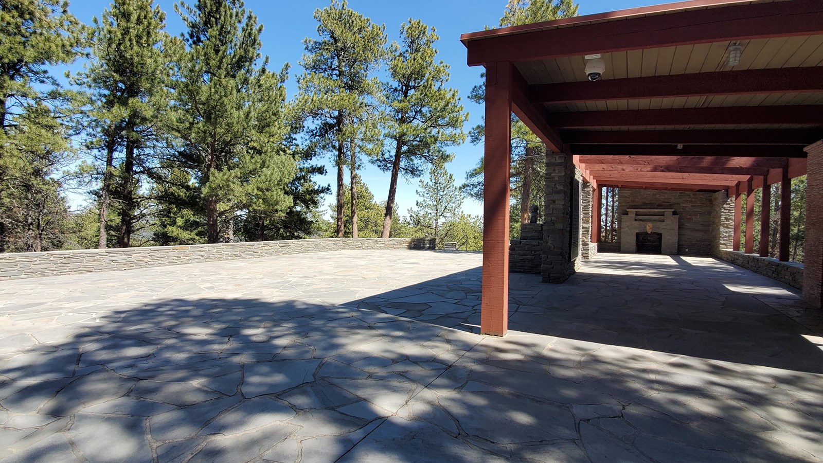 Grey stone terrace and a wooden framework structure with two stone fireplaces.